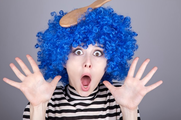 Chica sorprendida de cabello azul con peine pegado.