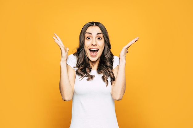 Chica sorprendida con cabello largo y oscuro y una sonrisa deslumbrante llena de emociones agradables, lo que se ve en su lenguaje corporal.