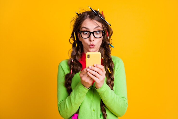 Foto chica sorprendida con corte de pelo a lápiz leer información en smartphone aislado sobre fondo de color amarillo