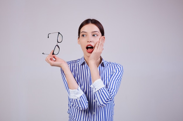 Chica sorprendida con gafas negras de computadora en mano