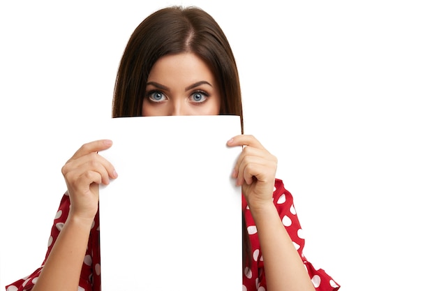 Foto chica sorprendida que cubre su rostro con una hoja de papel aislado en blanco