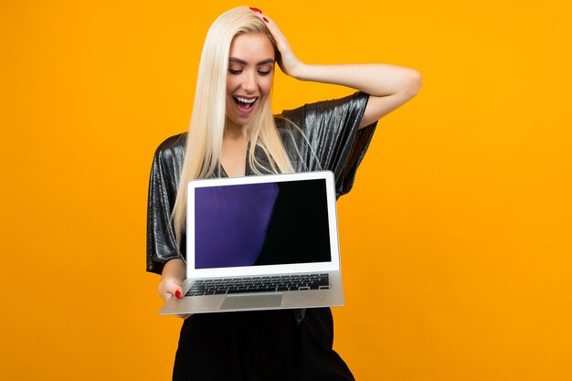 Chica sorprendida sostiene portátil con plantilla para página web en amarillo