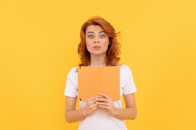 Chica sorprendida tiene cuaderno sobre conocimiento de fondo amarillo