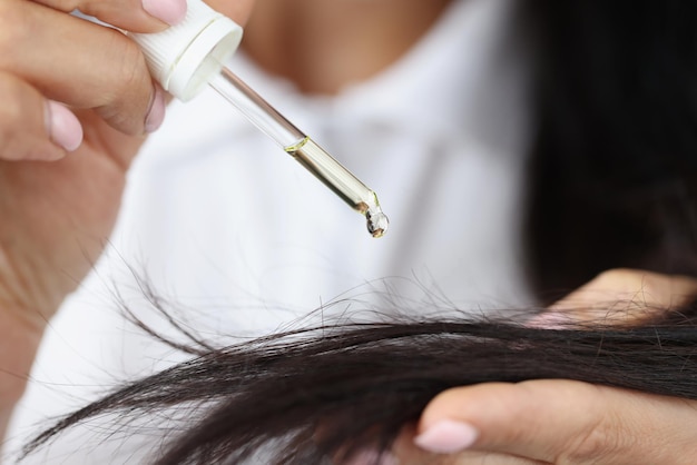 Chica sostenga el gotero con aceite de extracto de ricino cerca del cabello y aplique una gota