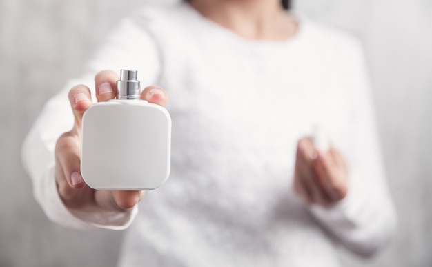 Chica sosteniendo una botella de perfume.