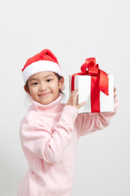 Chica sosteniendo una caja de regalo en suéter y gorro de papá noel