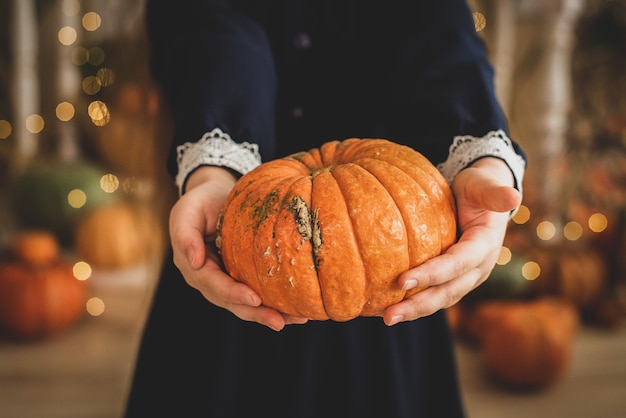 Chica sosteniendo una calabaza. vegetal naranja en manos de los niños. otoño, halloween, cosecha de naranja. luces, bokeh.