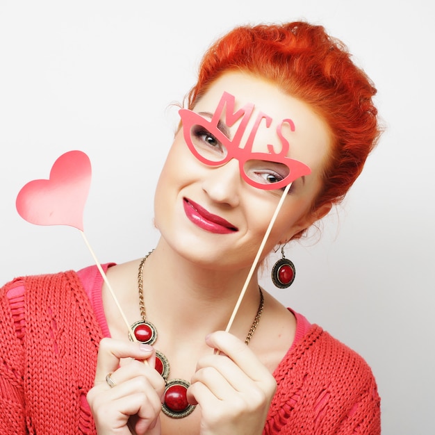 Chica sosteniendo un corazón de fiesta y gafas.