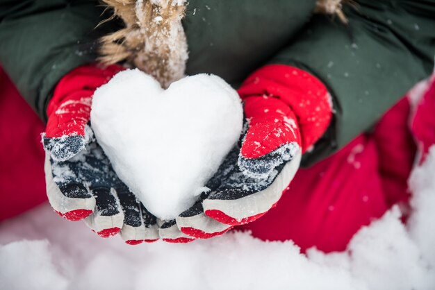 Chica sosteniendo un corazón de hielo en guantes rojos brillantes