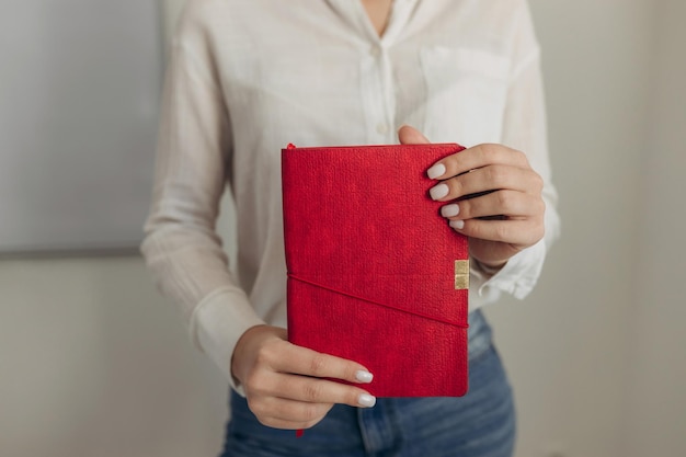 Chica sosteniendo un cuaderno rojo para escribir Retrato grande de un cuaderno