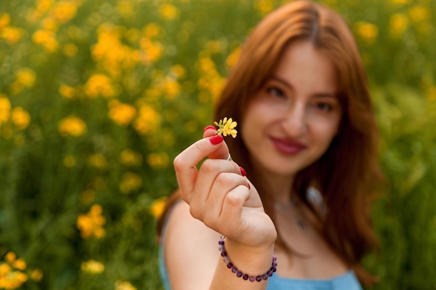 Chica sosteniendo una flor de colza amarilla en el campo