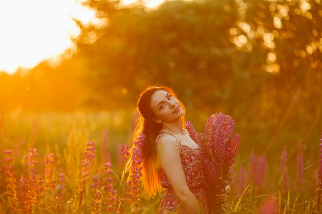 Chica sosteniendo flores. Morena en campo. puesta de sol