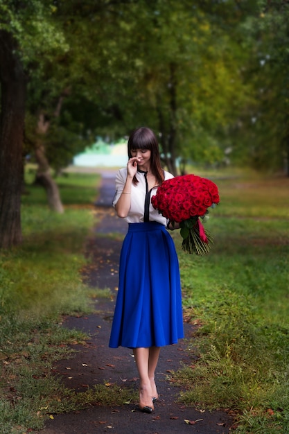 Chica sosteniendo un gran ramo de rosas