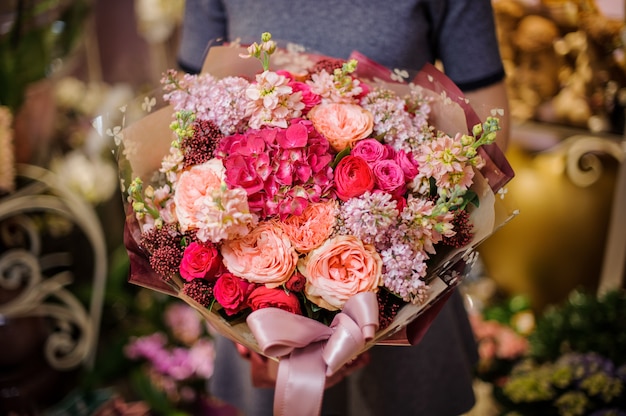 Chica sosteniendo un hermoso ramo de flores rosas y duraznos