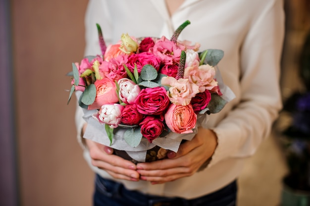 Chica sosteniendo un hermoso ramo de rosas con hojas verdes