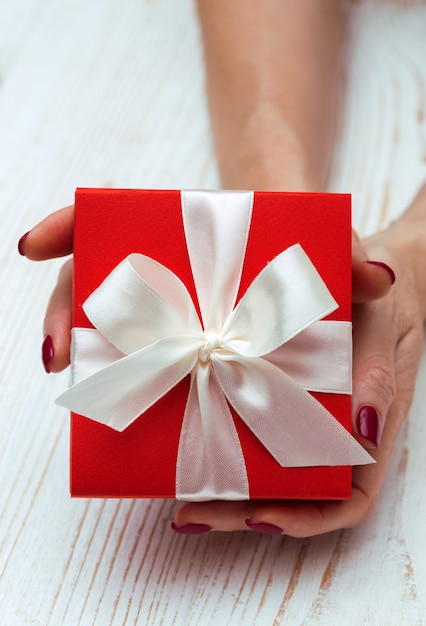 Chica sosteniendo un hermoso regalo para el día de San Valentín. caja roja y lazo blanco