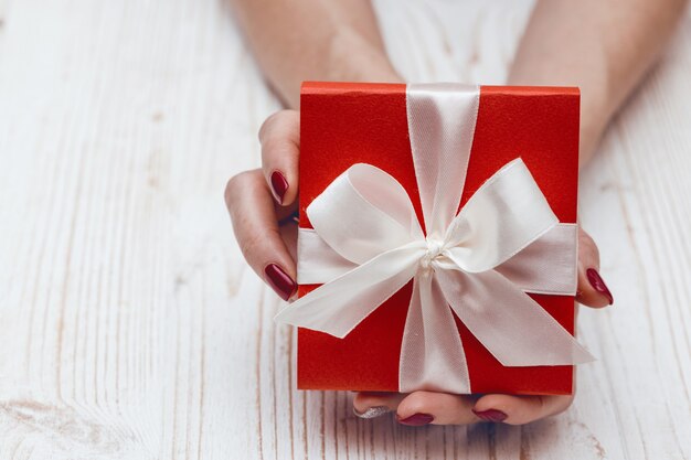 Chica sosteniendo un hermoso regalo para el día de San Valentín. caja roja y lazo blanco