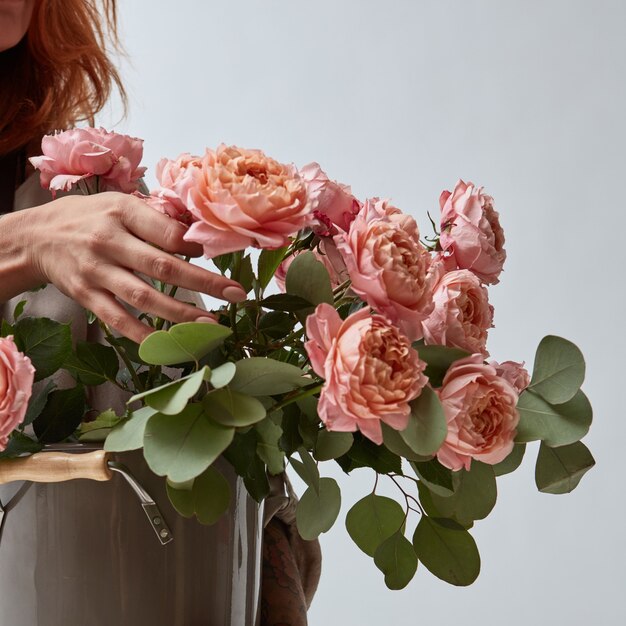 Chica sosteniendo un jarrón con un ramo de rosas