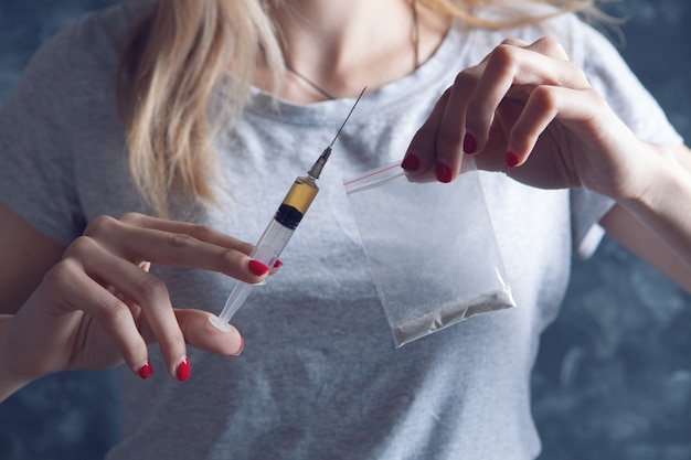 Chica sosteniendo una jeringa y un paquete de medicamentos