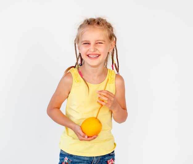 Chica sosteniendo una naranja con una pajita para jugo