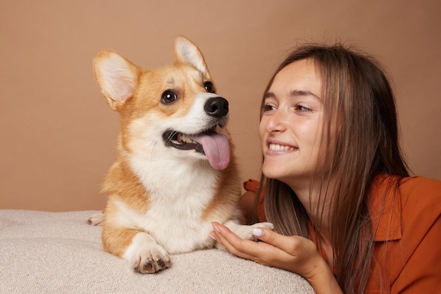 Foto chica sosteniendo la pata de pembroke perro corgi galés en el sofá amor por los animales