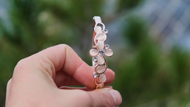 Chica sosteniendo una pulsera rosa con flores sobre un fondo verde natural