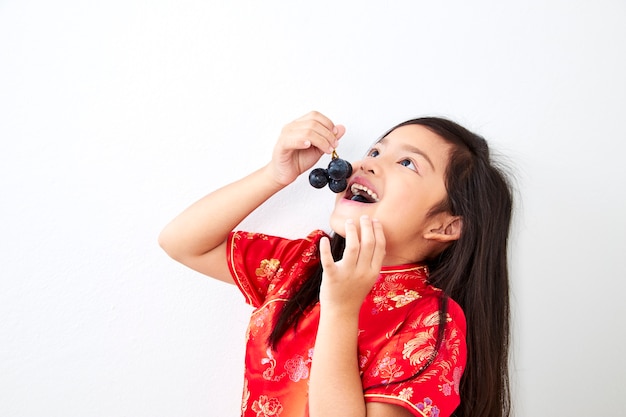 Chica sosteniendo un racimo de uvas comiendo