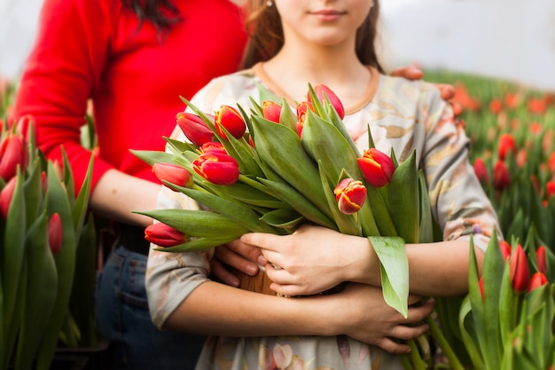 Chica sosteniendo un ramo de tulipanes cultivados en un invernadero