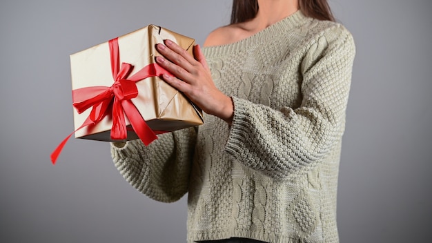 Chica sosteniendo un regalo en un suéter de punto.