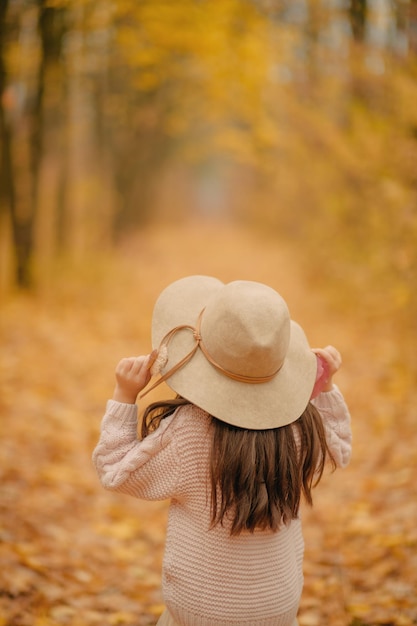 chica sosteniendo un sombrero con las manos sobre un fondo de otoño