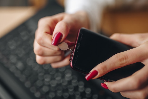 Chica sosteniendo una tarjeta mini sim en sus manos con manicura roja