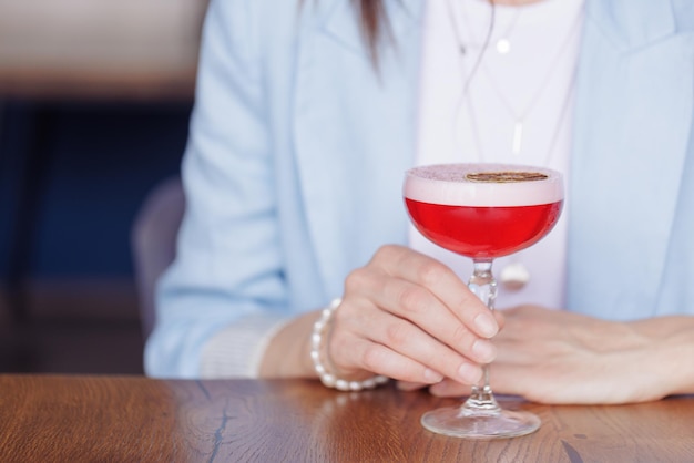 Chica sosteniendo un vaso con un cóctel en una cafetería o restaurante concepto de restaurante de primer plano