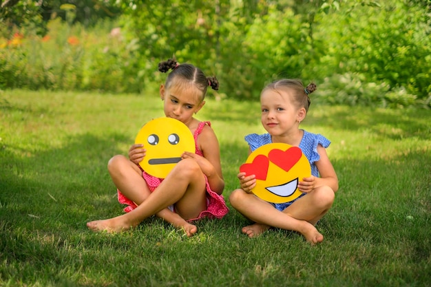 Una chica sostiene un emoticon triste lloroso segunda cara sonriente con corazón en lugar de ojo