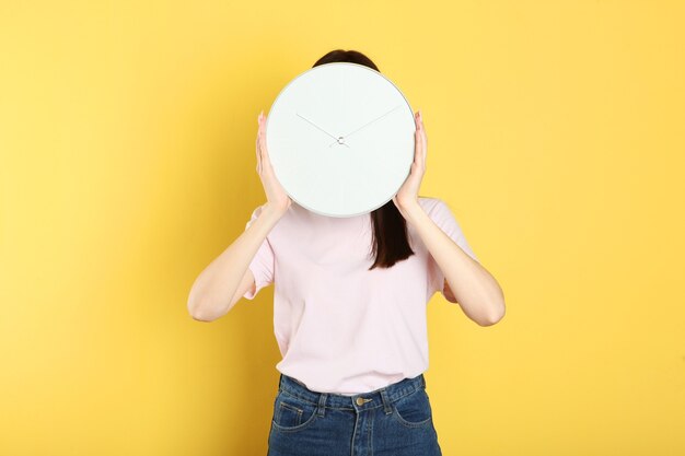 Chica sostiene un reloj mecánico sobre un fondo de color