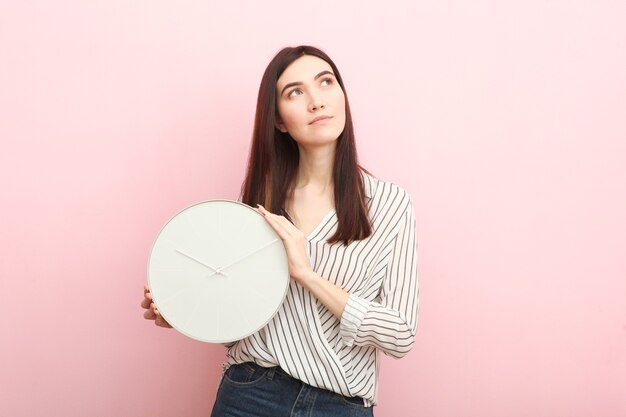 Chica sostiene un reloj mecánico sobre un fondo de color