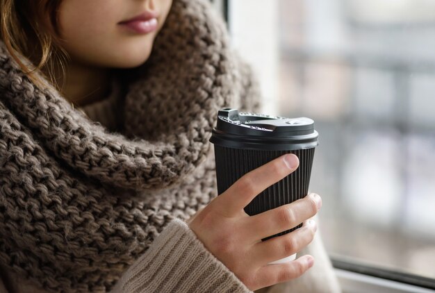 Chica sostiene una taza de papel con café