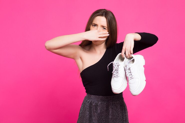 la chica sostiene zapatillas apestosas y cierra la mano con el olor de la nariz a los zapatos