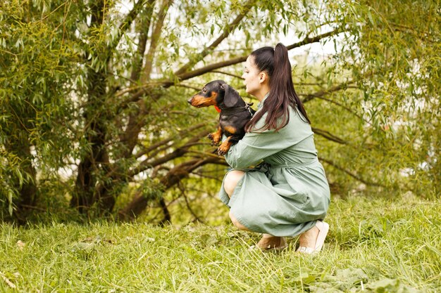 Chica con su amigo perro mascota en el parque dachshund en manos de su amante