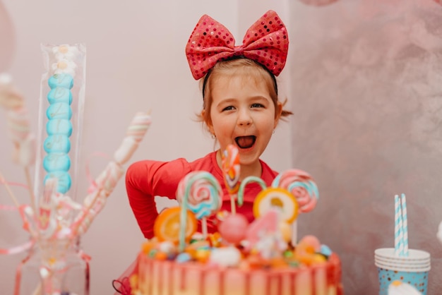 Chica con su pastel de cumpleaños, tarjeta de feliz cumpleaños, una linda niña celebra su cumpleaños rodeada de regalos. foto de alta calidad