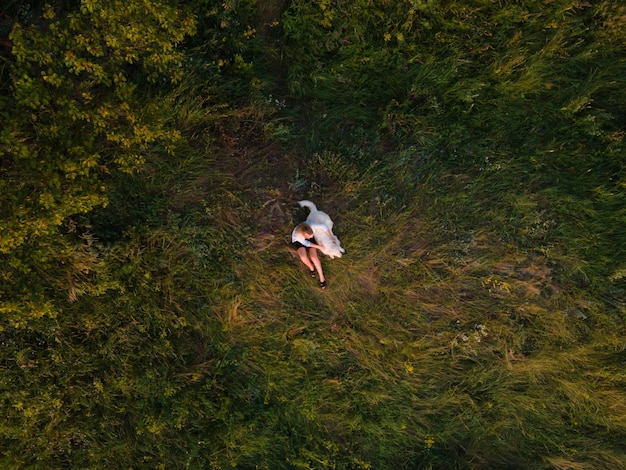 Chica con su perro sentado en el prado cubierto de hierba verde