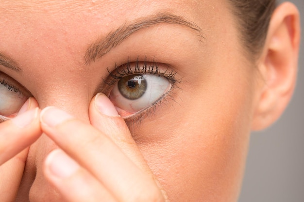 Foto chica suaviza las bolsas de los ojos con el dedo