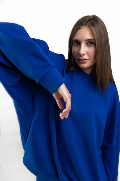 Chica en una sudadera con capucha deportiva en azul sobre un fondo blanco.