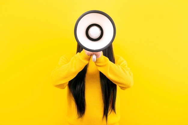 Chica con un suéter amarillo con un megáfono