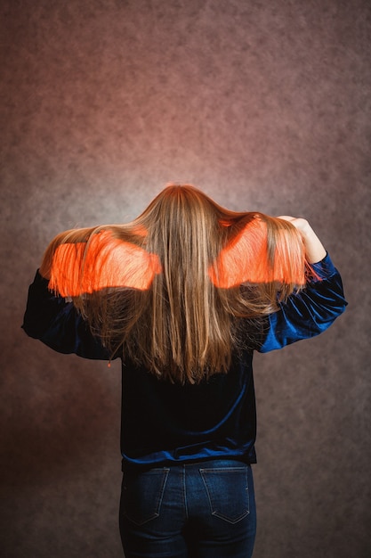 Foto chica con un suéter azul sobre un fondo gris. tiene un cabello hermoso y posa hermosamente.