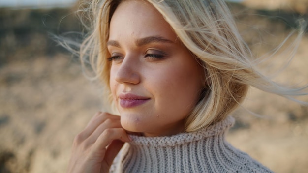 Chica suéter disfrutando del viento retrato de otoño cabello soplando en cara de modelo rubia