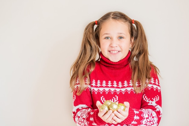 Chica en suéter de Navidad con adornos navideños dorados