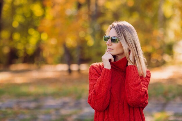 una chica con un suéter rojo camina en otoño en el parque el concepto de la temporada de otoño