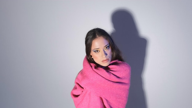 Foto una chica con un suéter rojo posa sobre un fondo claro