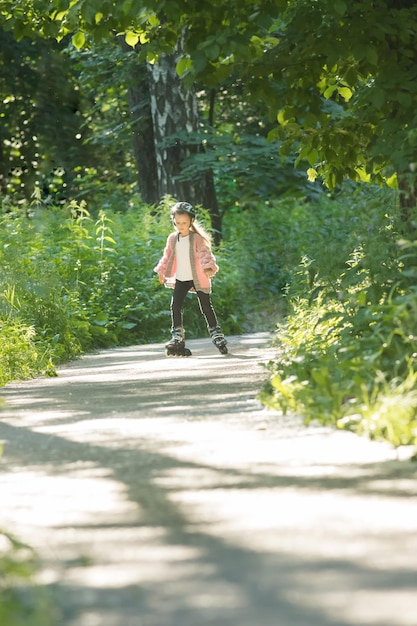 Una chica con suéter rosa patinando en el parque sobre sus ruedas