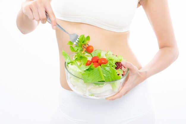 Chica en un sujetador deportivo blanco tiene una ensaladera.